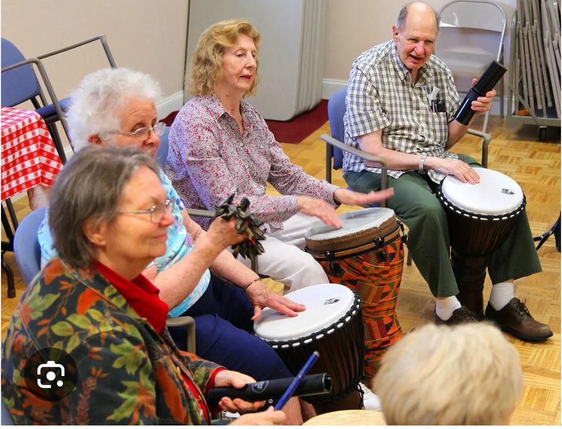 Elderly participants playing hand drums at a senior center