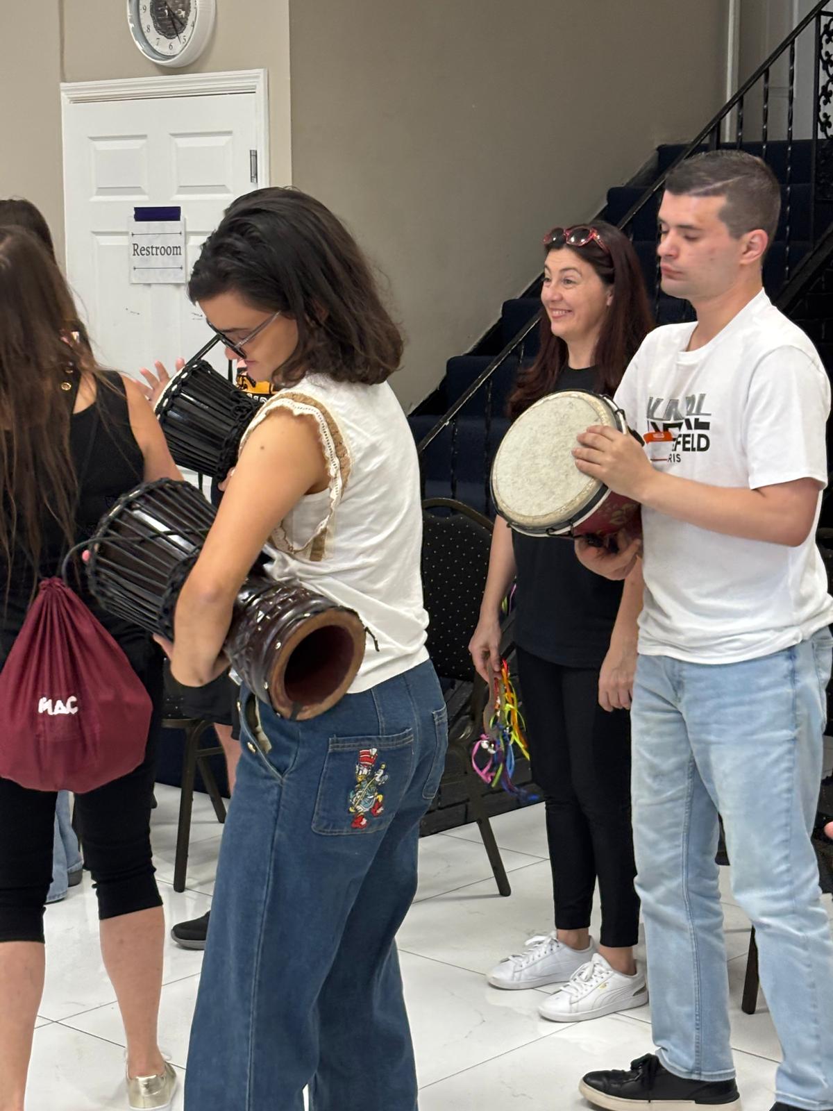 Young adults playing hand drums together indoors